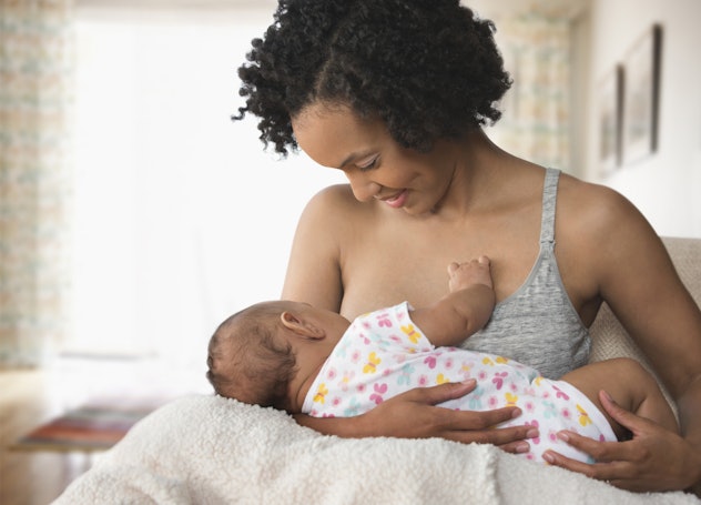 A mother breastfeeding her baby and smiling