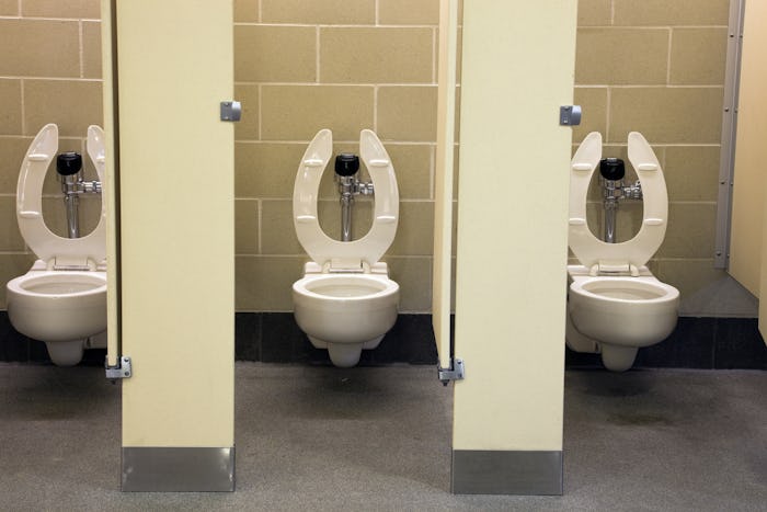 A public restroom with three open stalls and visible toilet seats