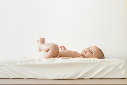 A baby laying on a white mattress 