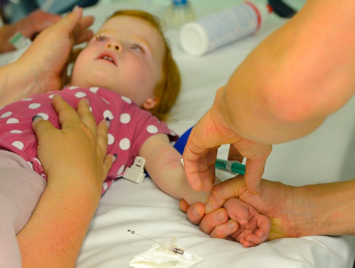 A nurse holding a hand of a little girl