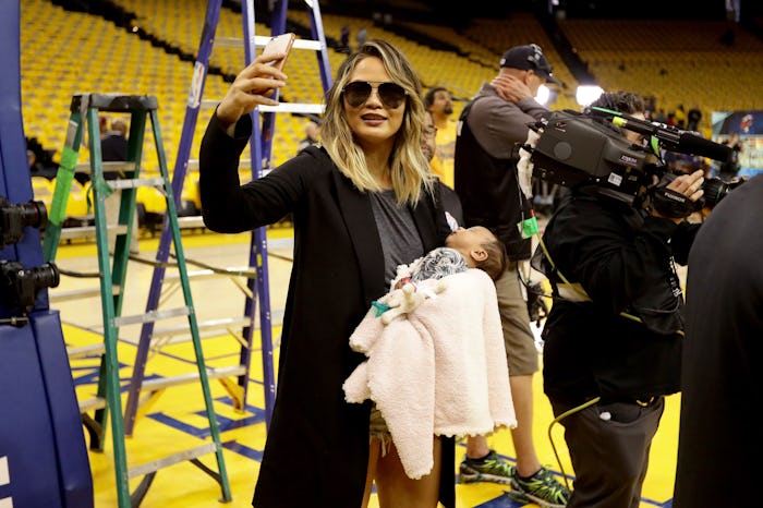 Chrissy Teigen taking an Instagram photo on her phone with her daughter Luna