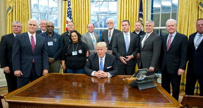 Donald Trump sitting at the White House surrounded by his colleagues