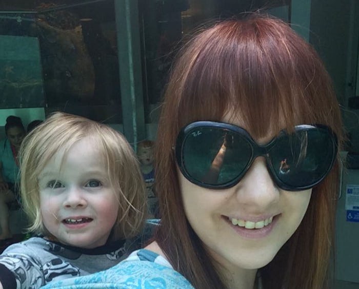 Elizabeth Broadbent smiling with black sunglasses and carrying her baby on her back who is also smil...
