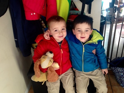 Two brothers in jackets hugging each other and smiling for a picture