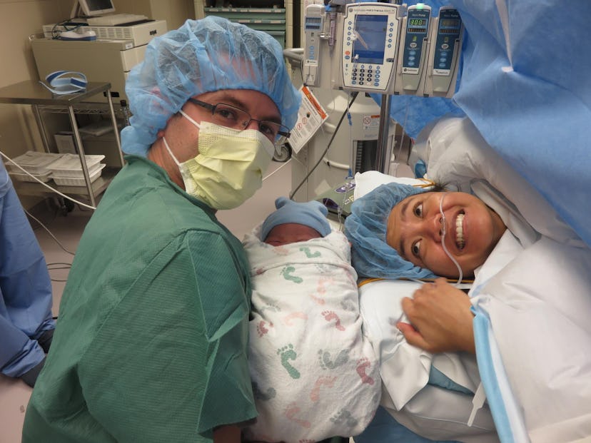 A doctor taking a picture with a newborn and his happy mom after the labor