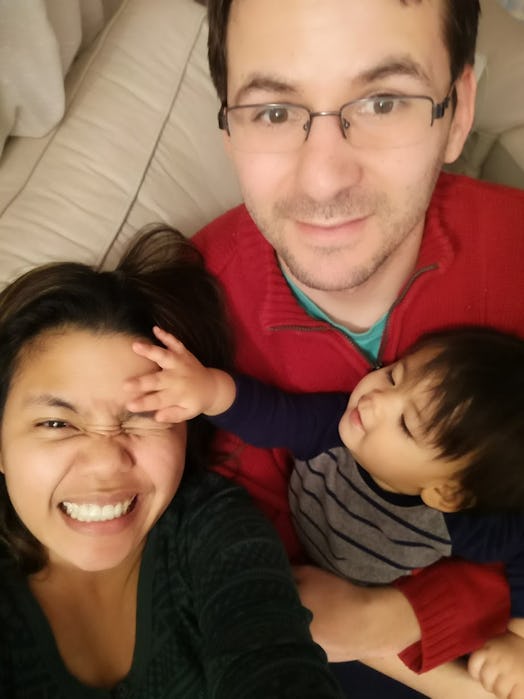 Selfie of a happy parents holding a child with his hand on a mother's forehead.