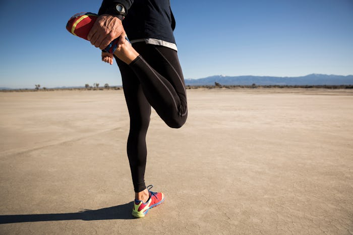 An athlete wearing leggings and stretching before engaging in a run