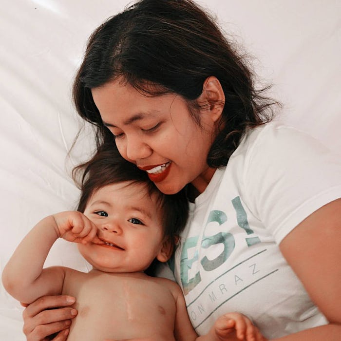 A mother in bed with her toddler who had heart surgery, both smiling