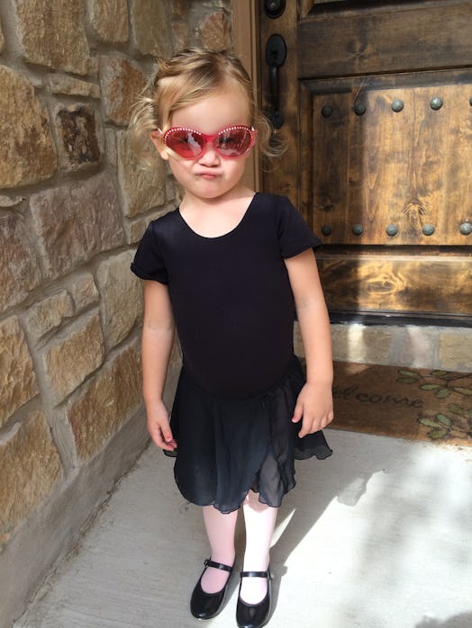 Crystal Henry's daughter posing in a black dress and pink sunglasses