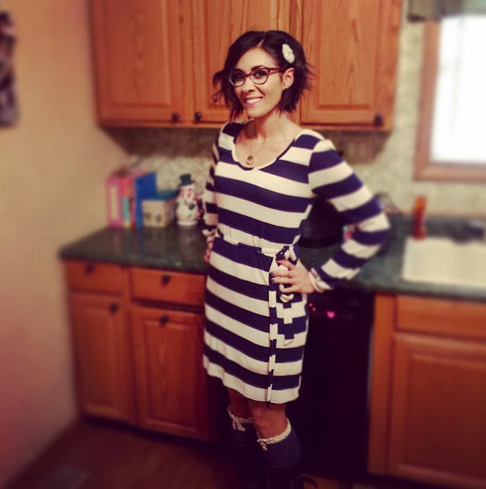 Mother with an eating disorder in a striped dress standing in her kitchen and smiling
