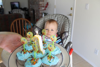 Samantha Taylors' son sitting in a feeding chair and having cupcakes with the number one in front of...