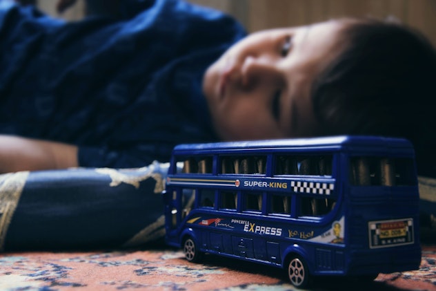 A child with developed PANDAS lying on the floor with a bus toy next to him