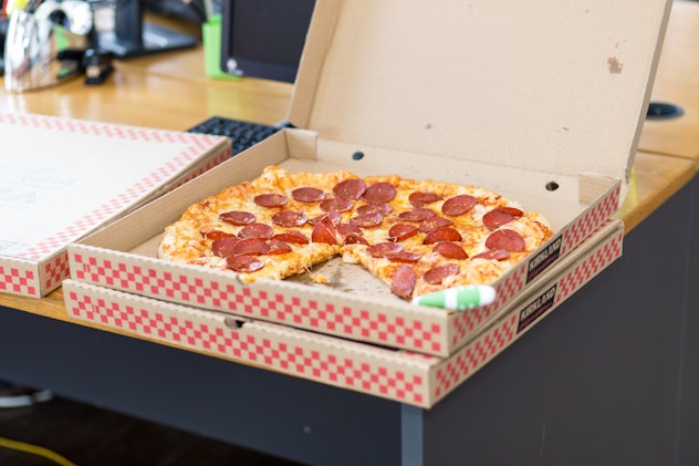 A pepperoni pizza in a box with one slice missing