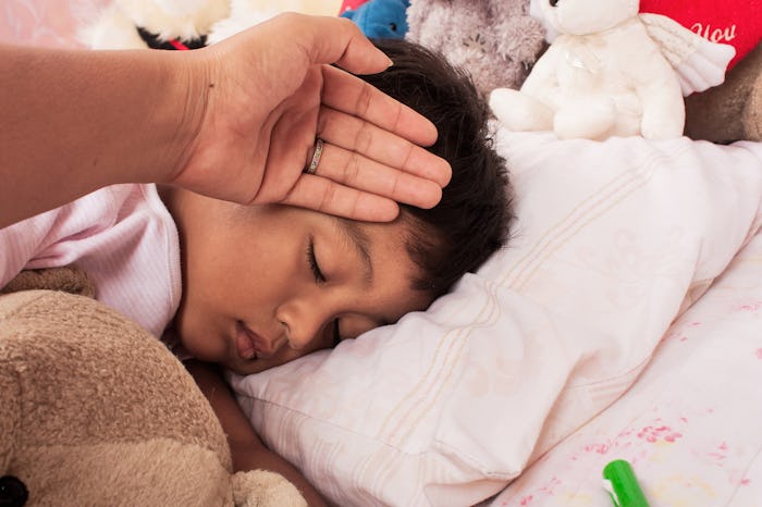 A mother's hand touching a forehead of a sleeping child with a Streptococcal infection