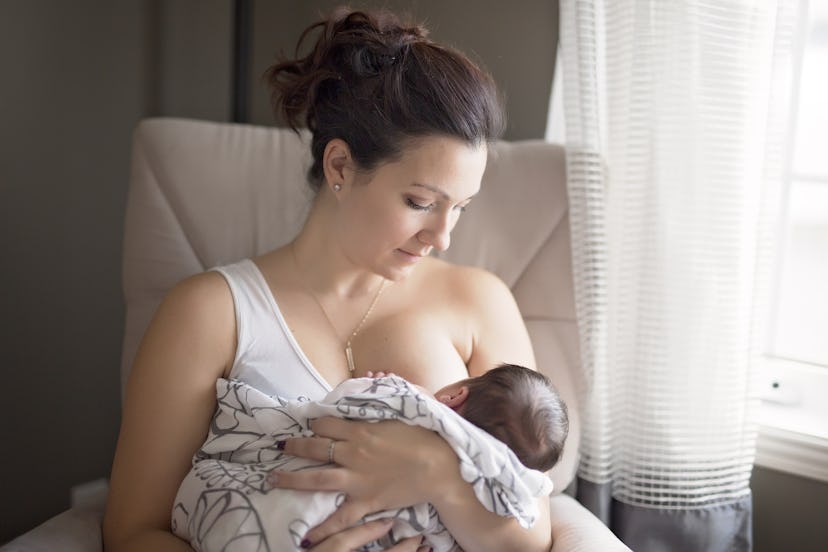 A mom breastfeeding her baby that's covered in a blanket 