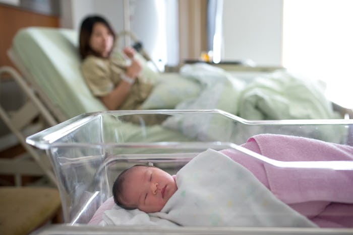 Woman lying in a hospital bed with her baby lying next to her