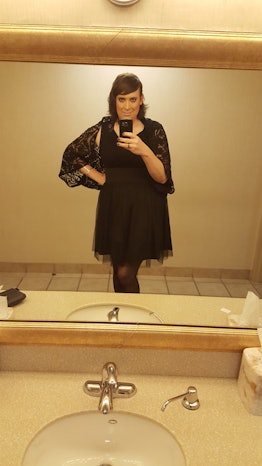 Katelyn Burns taking a mirror selfie while wearing a black cocktail dress and a matching scarf