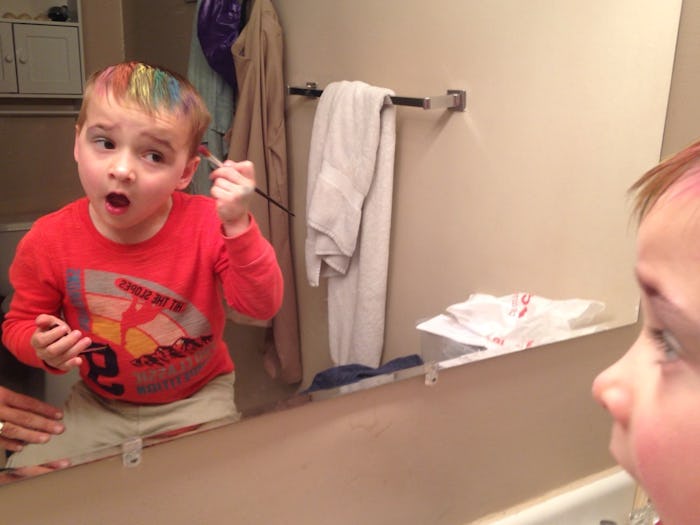 A 4-year-old boy putting unicorn makeup on his head