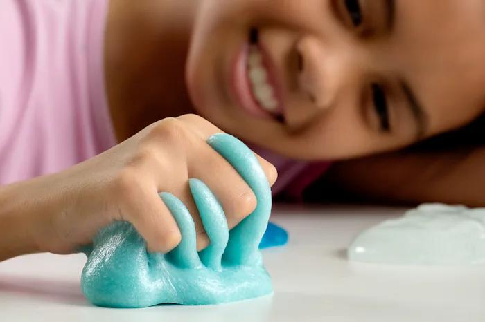 A girl playing with light blue slime she made without detergent