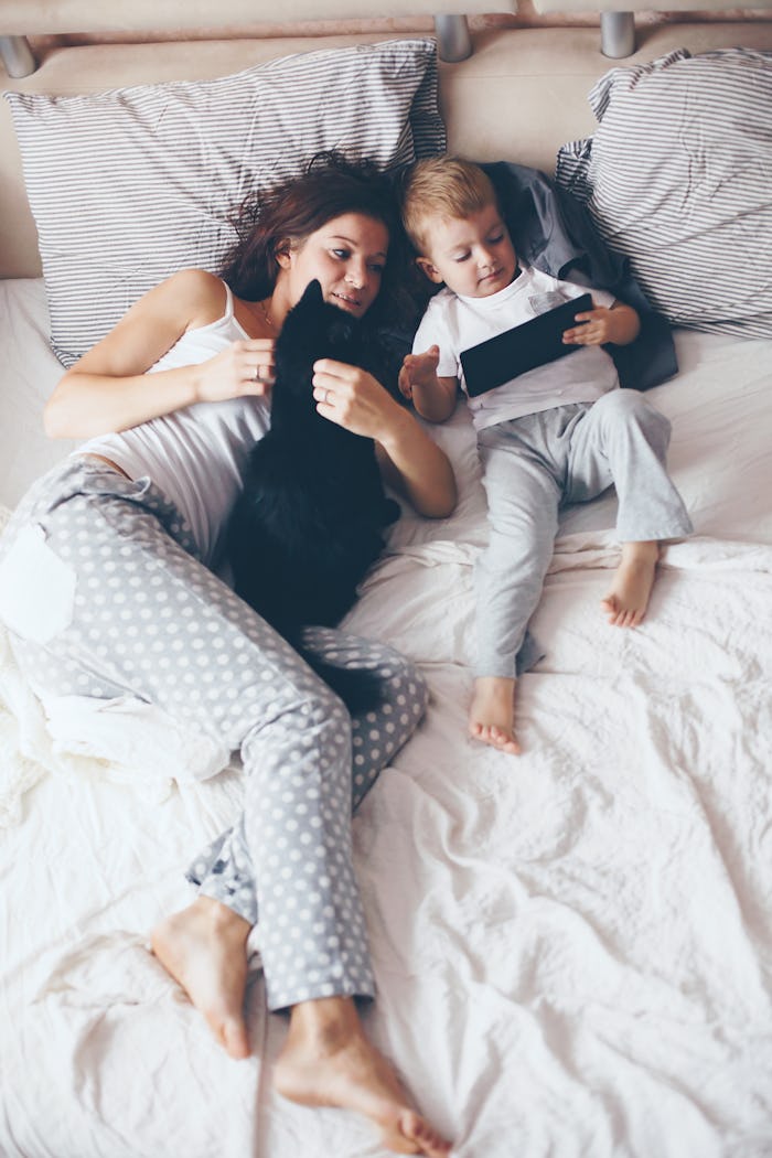 A mom in bed with her kid watching a TV show the mom likes on her iPad