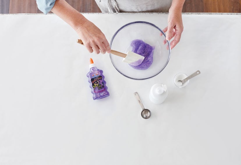 A picture of a parent mixing up a bowl of purple Elmer's Glue slime. 