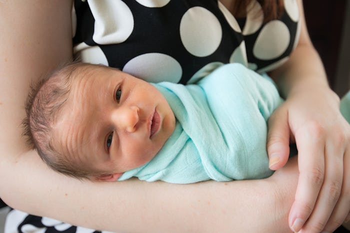 A mother holding a newborn baby wrapped in a light blue blanket