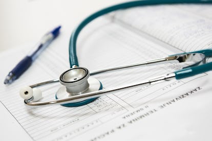 A stethoscope and a pen placed on a patients chart showing their high cholesterol