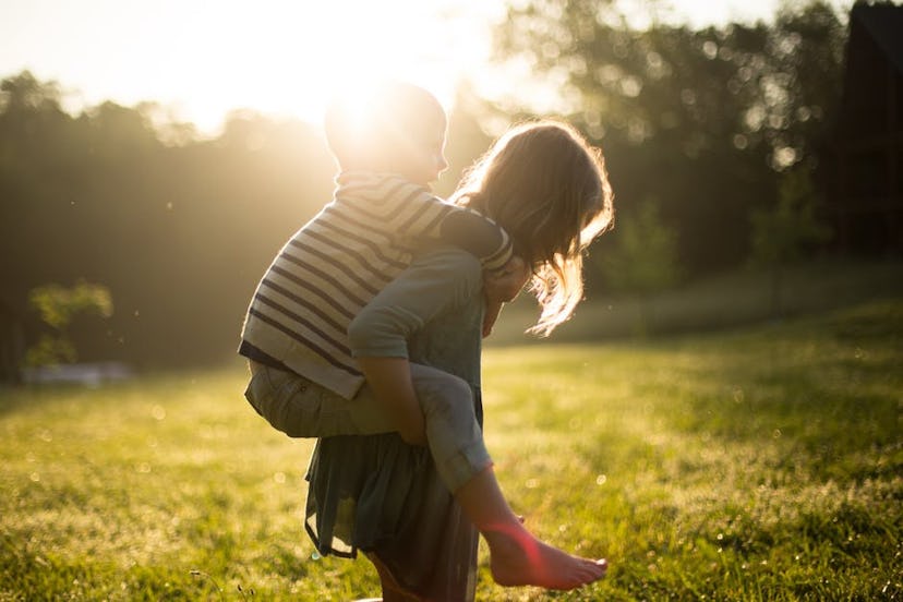 An older sister carrying her brother on the back