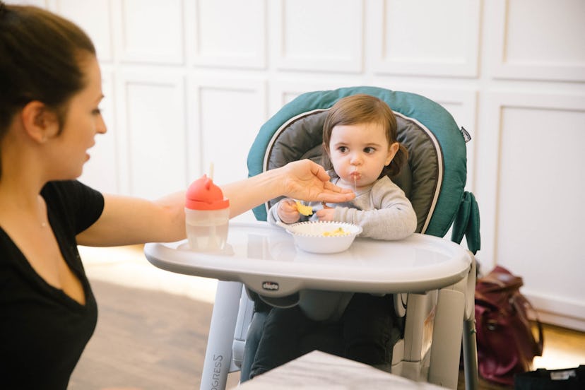 A baby eating while sitting in a chair