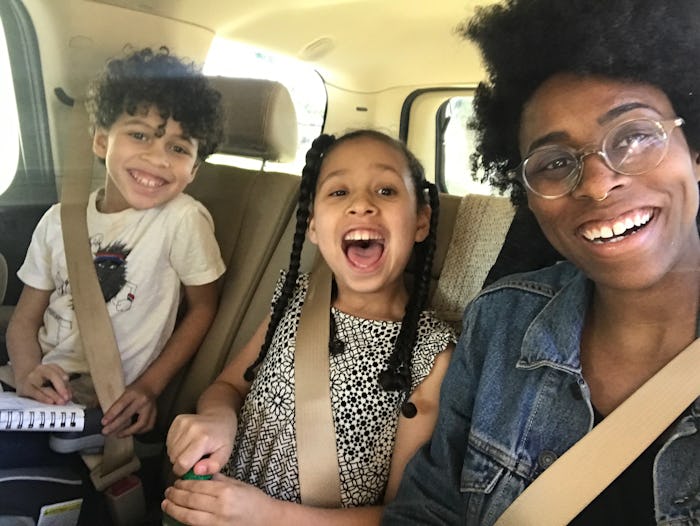Woman and her two children sitting in the car smiling at the camera