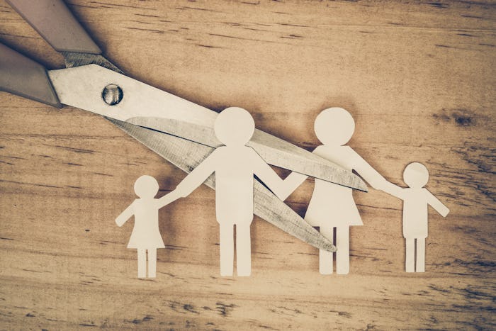 A family holding hands paper cutout piece being snipped with scissors representing divorce