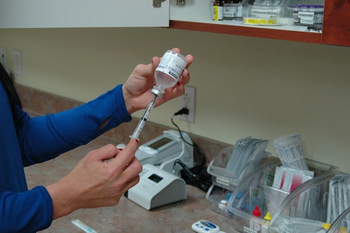 A closeup of a doctor extracting the vaccine from a bottle using a syringe