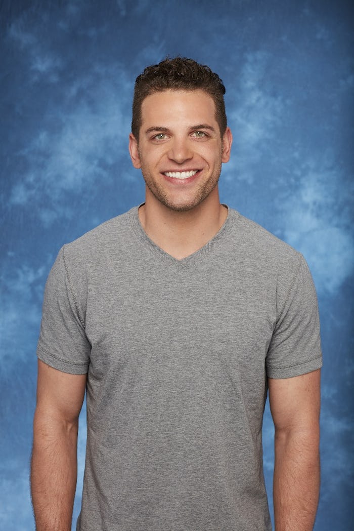 Adam from 'The Bachelorette' posing and smiling in a grey shirt with a blue background