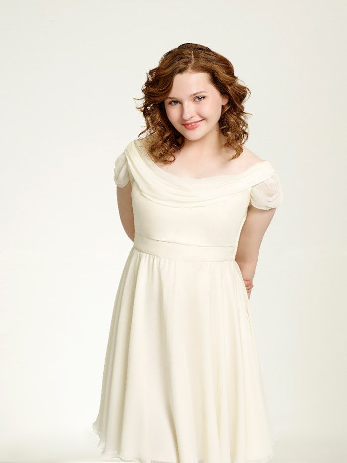 Abigail Bresling standing, smiling, and posing in a sleeveless cream white dress