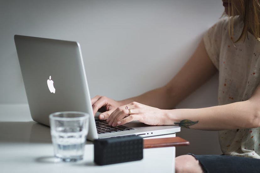 A girl working on her laptop with a glass of water next to it