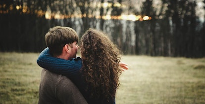 A curly-haired woman hugging her partner in a park