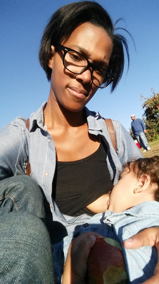 A short hair mother holding and breastfeeding her kid in the park