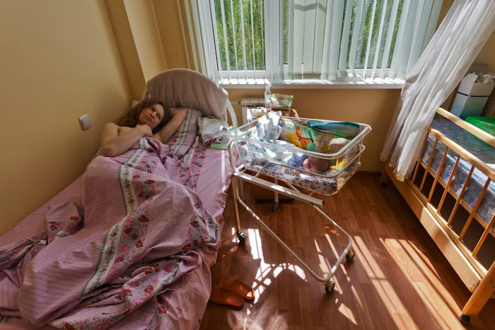 A woman lying in her bed after giving birth with her baby next to her in its own bed