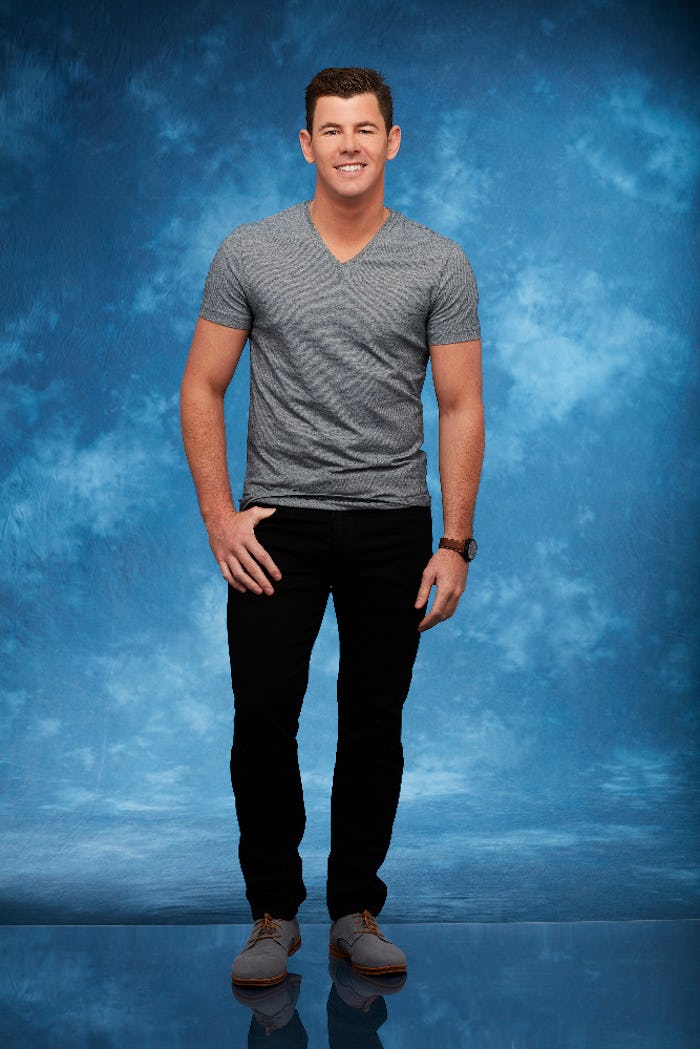 Lucas Yancey, standing and smiling in a grey shirt, and black pants with a blue background