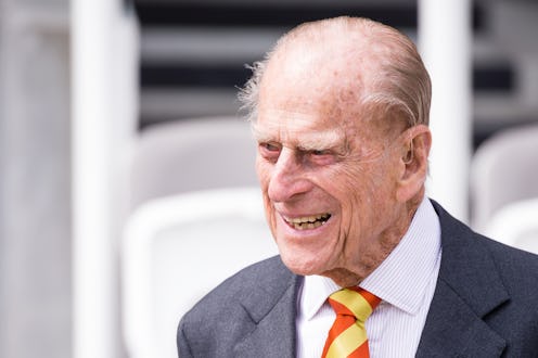 A closeup of Prince Phillip in a grey blazer, white button-up, and yellow and red tie