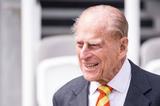 A closeup of Prince Phillip in a grey blazer, white button-up, and yellow and red tie 
