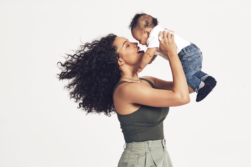 A curly hair mom lifting up her modern styled baby 
