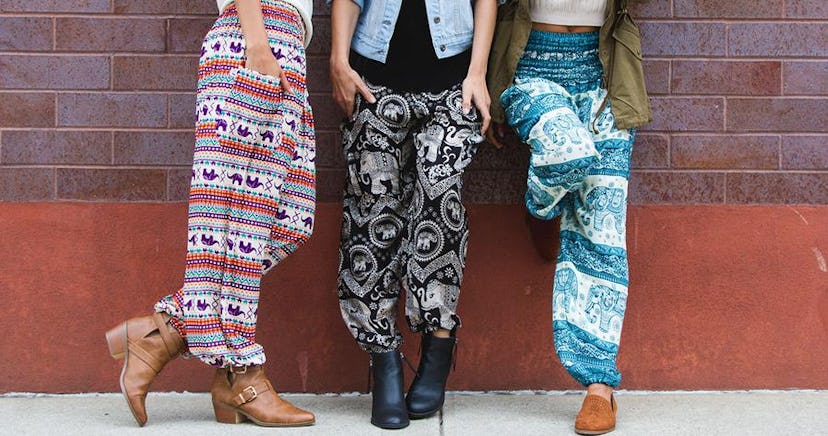 Three girls standing in front of the wall wearing different colorful elephant pants.