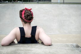 A view from the back of a woman leaning against a wall, experiencing depression due to PCOS