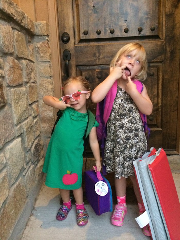 Two girls stand in a brick hallway in brightly colored clothing, ready for school, making silly face...