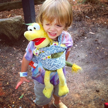 A little girl carrying a stuffed toy in a wrap on her chest 