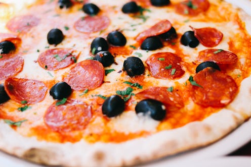 A pizza with olives and pepperoni served on a plate
