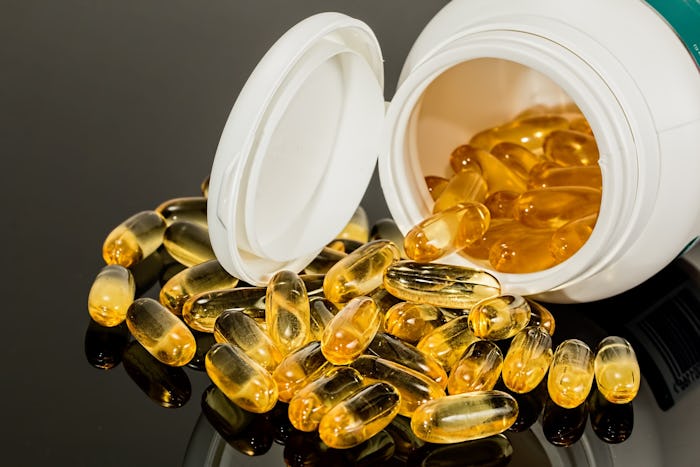 Prenatal vitamins spilling out of a pill bottle which is lying on its side