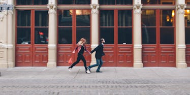 A couple of adults with ADHD holding hands while running on the sidewalk.