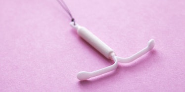 A white IUD placed on a pink surface